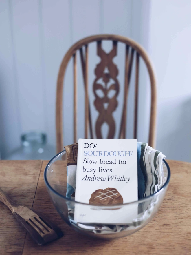 Book in glass mixing bowl on kitchen table