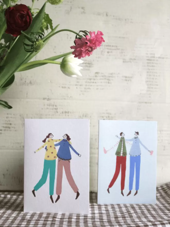 greetings cards with best friends on, female and male next to bunch of flowers