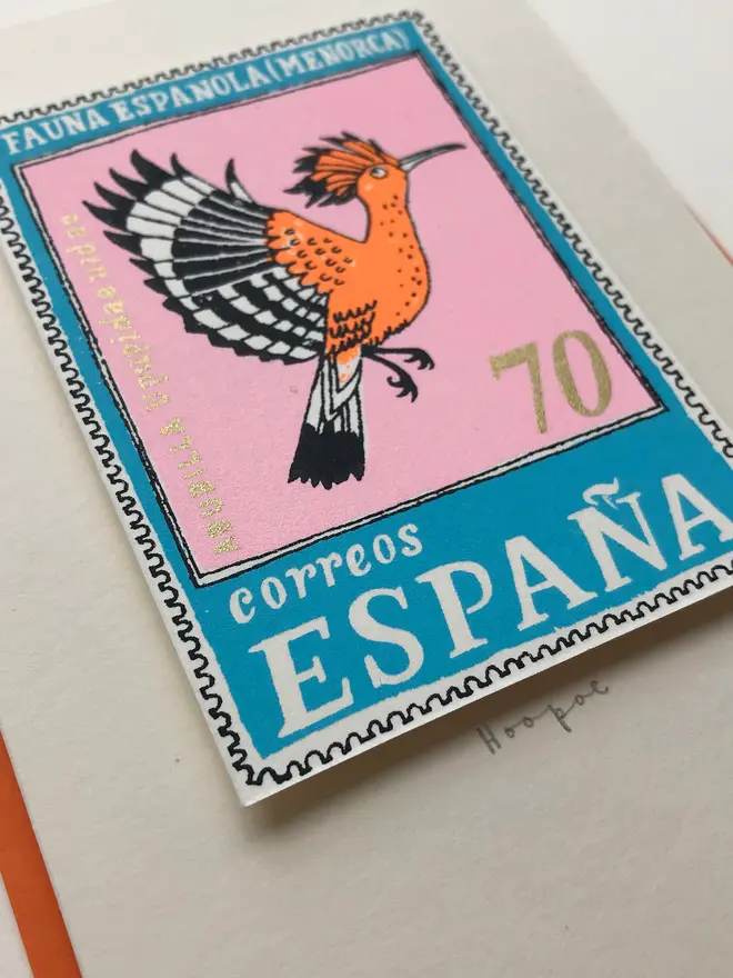 Bird Stamp Card Spain/ Hoopoe Card, a white card with a bird design in the middle against an orange envelope on a white background. 