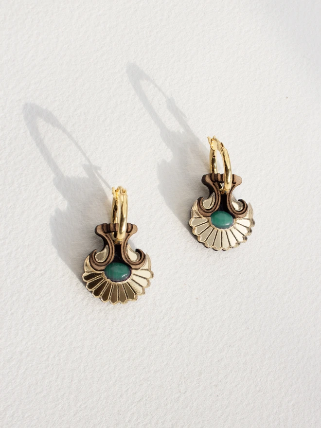 Pair of gold hoop earrings with natural stones on a light gray background
