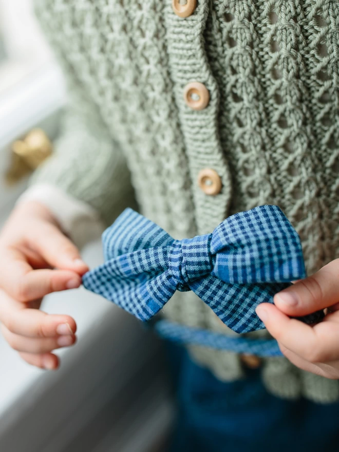 Little girls hands holding a blue gingham Alice Band