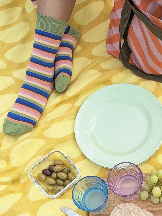 Organic Cotton Throw, a yellow cotton throw sitting on a ground with a picnic. 
