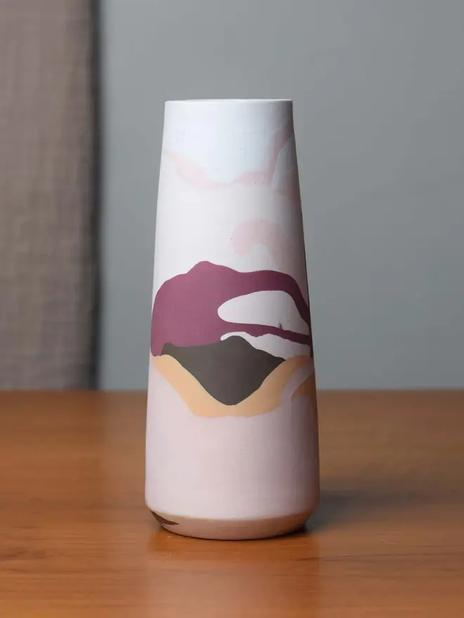 vase on wooden table, vase has streaky pattern in shades of purple, brown, and pale pink