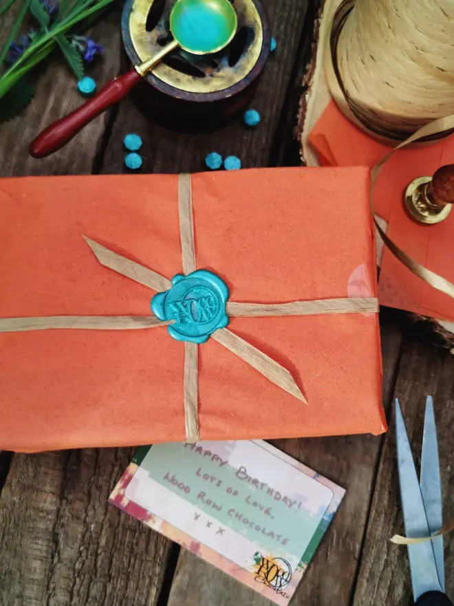 orange gift wrapped box with blue stamp seal and handwritten note