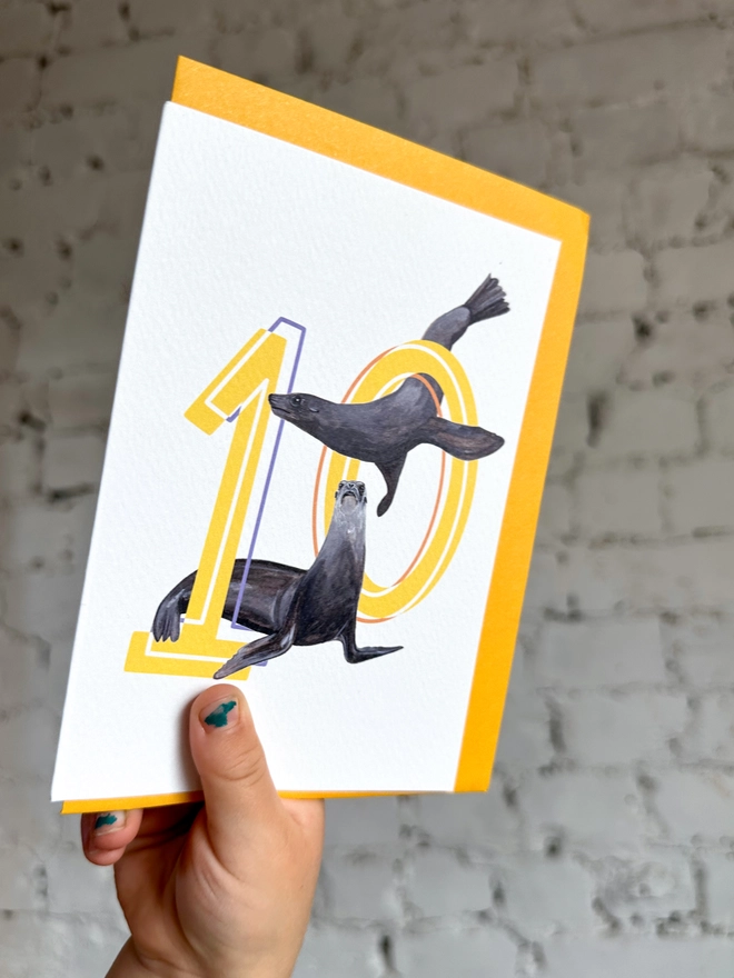 Number ten card with yellow numbers with sea lion illustrations and a yellow envelope
