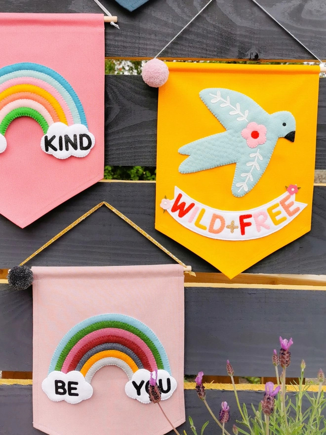 Three fabric banners on a garden fence