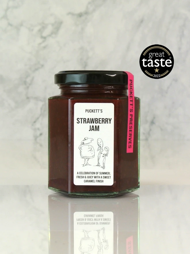 british strawberry jam. a jar of strawberry jam photographed on a marble background. 