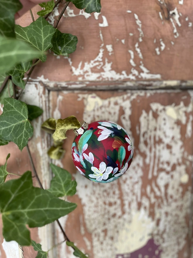 Hand painted floral ceramic bauble paperwhite flowers on a rich red background 