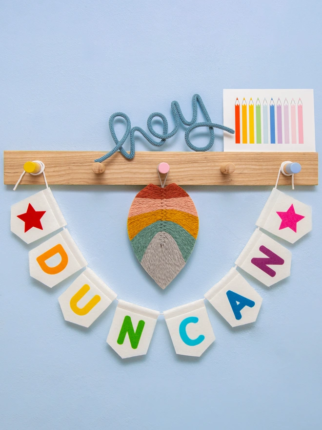 Personalised children's bunting. The text is a mix of bright rainbow colours on white felt flags. 