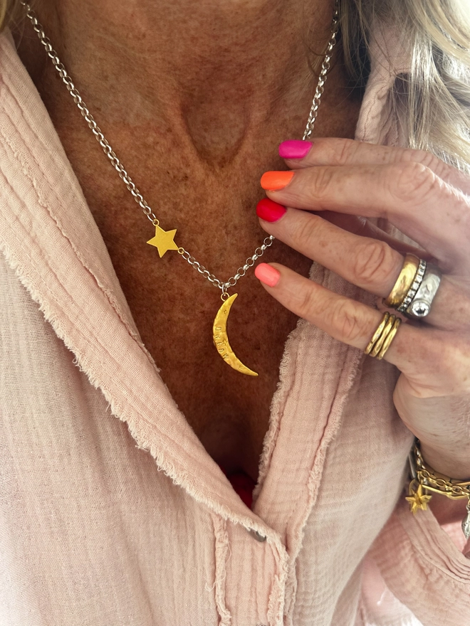 model wears a textured gold moon charm sits on a sterling silver heavy belcher chain, with linked gold cosmo star charm