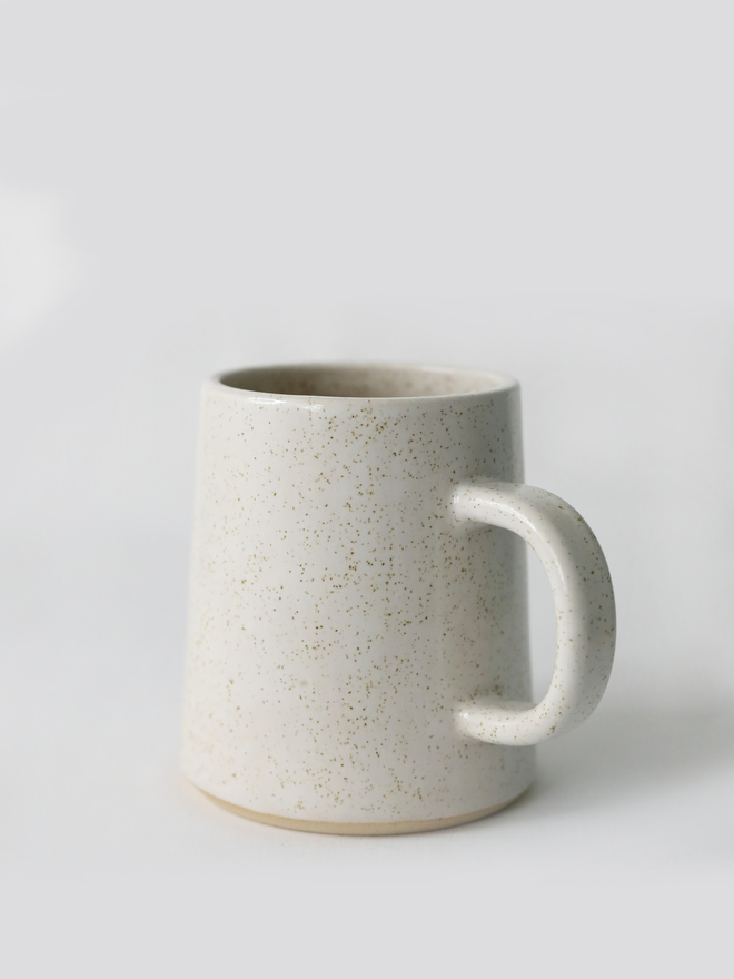 A handmade ceramic pint mug in pepper white glaze with a chunky loop handle, photographed against a plain light grey background
