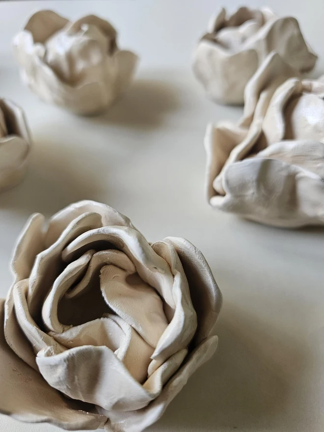 hand-sculpted ceramic flower in a soft cashmere glaze, featuring individually crafted petals and natural texture. Each unique piece is wall-mountable with a carved keyhole on the back