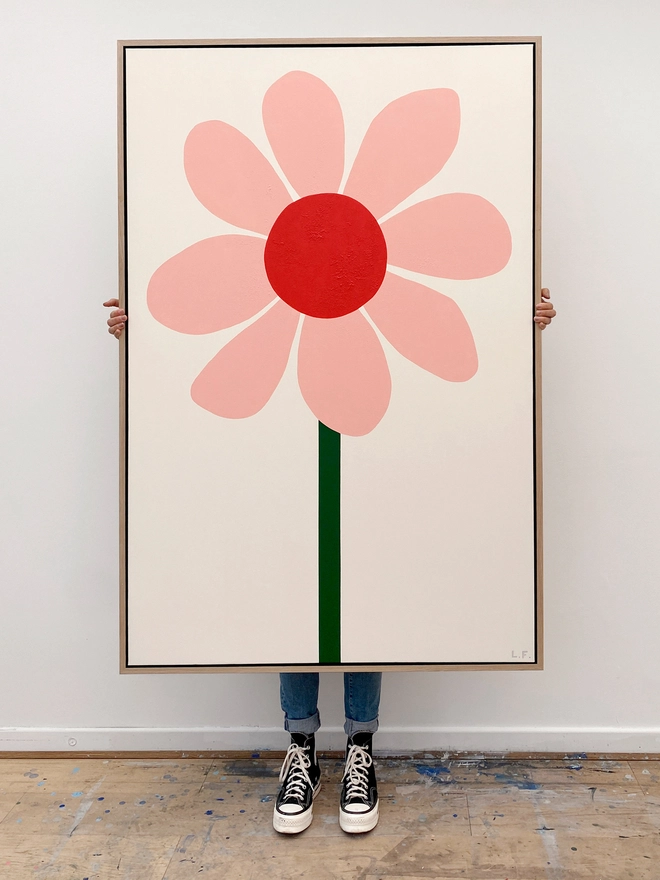 Giant pink and red flower painting with person holding it behind so only legs visible