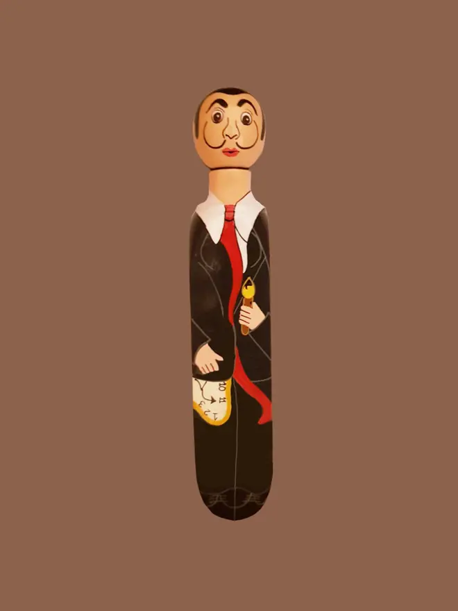 Wooden Door Stopper (Salvadoor), a colourful wooden door stop sitting on a brown surface. 