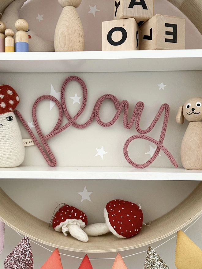 'Play' knitted wire word sign in a pink 'dusty rose' colour.