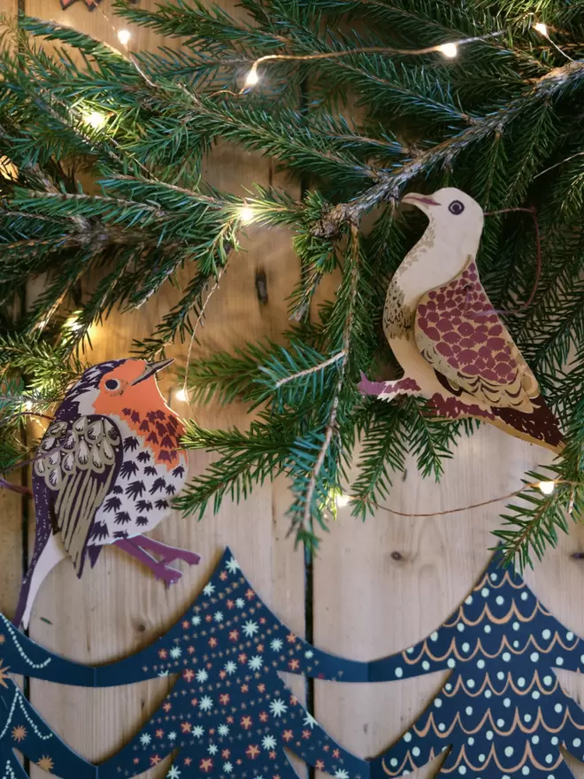Winter birds on Christmas tree branch with warm twinkling lights