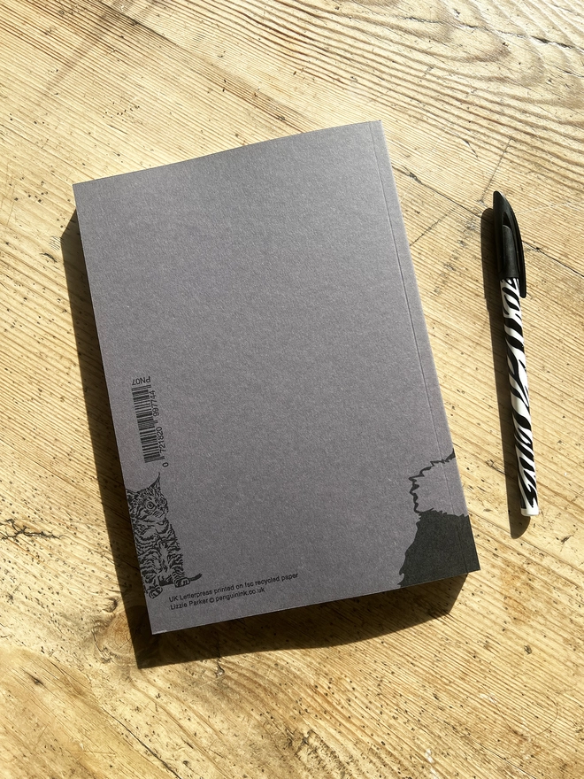 Back of the note book with one of the paws wrapped around on the back.