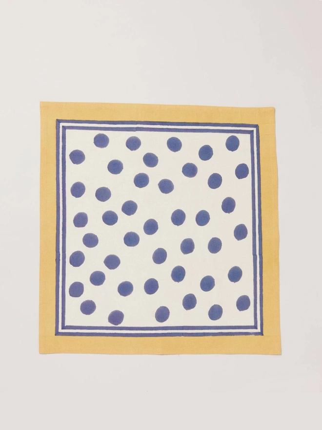 Single block printed napkin in navy dot design onto white ground with a yellow border