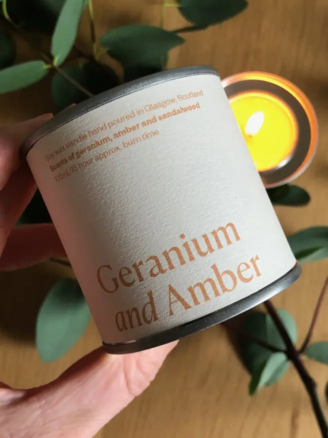 Geranium & Amber Candle against a plant background. 