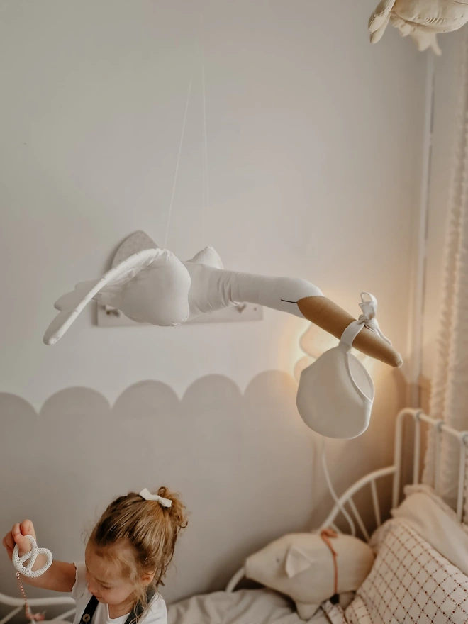 Flying Stork Hanging Decoration, a hanging stork decoration suspended in a child's bedroom. 