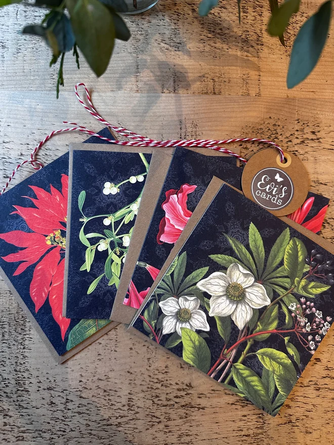 A set of Botanical Christmas cards showing the 4 designs of an Amaryllis, Mistletoe, Christmas Rose and Poinsettia. The floral designs are set against a black background which gives a traditional look and makes the design stand out.  