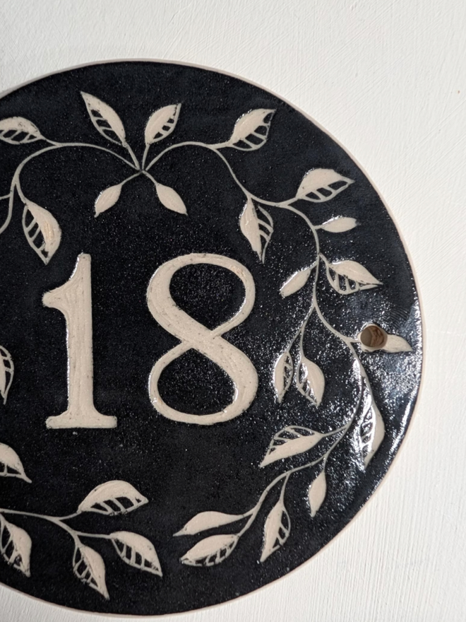 Custom Round Ceramic House Number with Leaves. A house number in black.