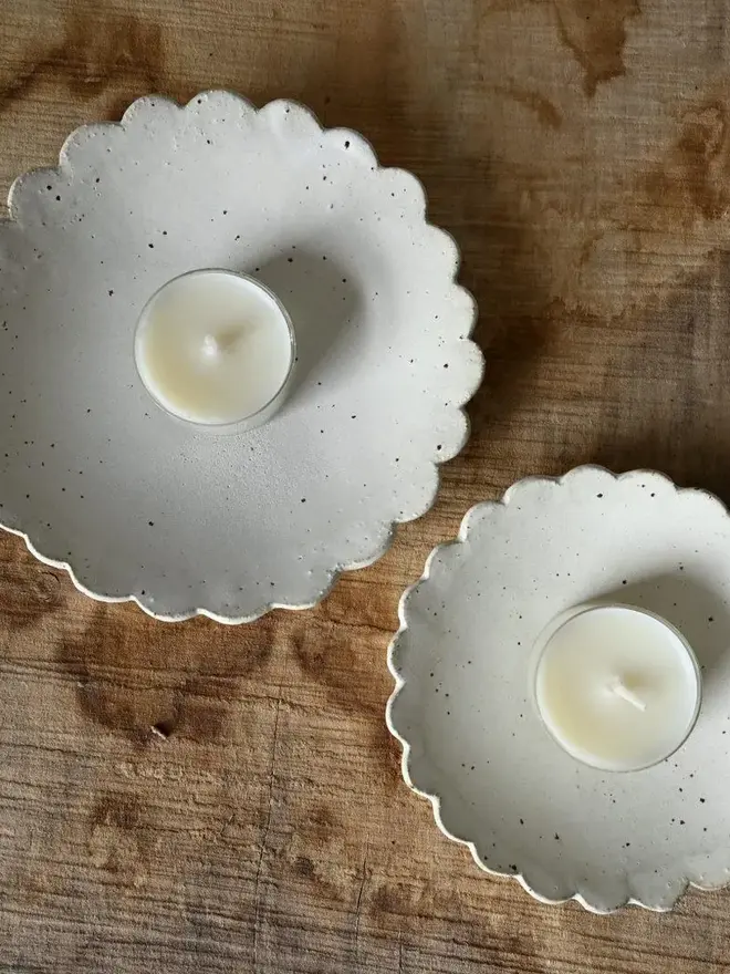 Handmade Scalloped Ceramic Dish, a pair of ceramic dishes on a wooden surface. They are accompanied by some candles. 