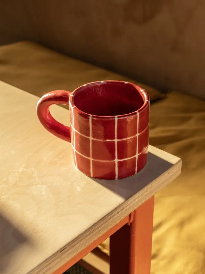 Grid Chunky Mug, a colourful mug with a grid pattern on a white table top surface. 