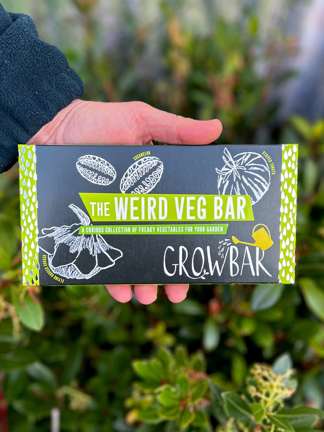 The Kids' Weird Vegetable Growbar held by our gardener in front of a background of plants. 