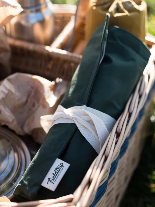 'mess kit' cotton cutlery and utensil roll. a pack of picnic utensils in a cotton roll, photographed in a wicker picnic basket.