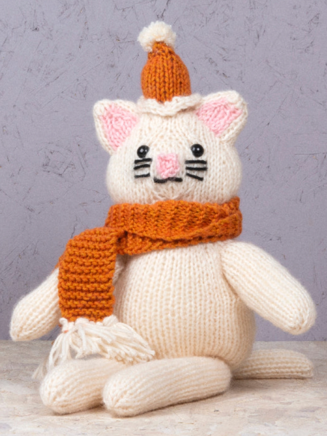 Cat in Knitwear Knitting Kit. A cream cat with orange knitwear.