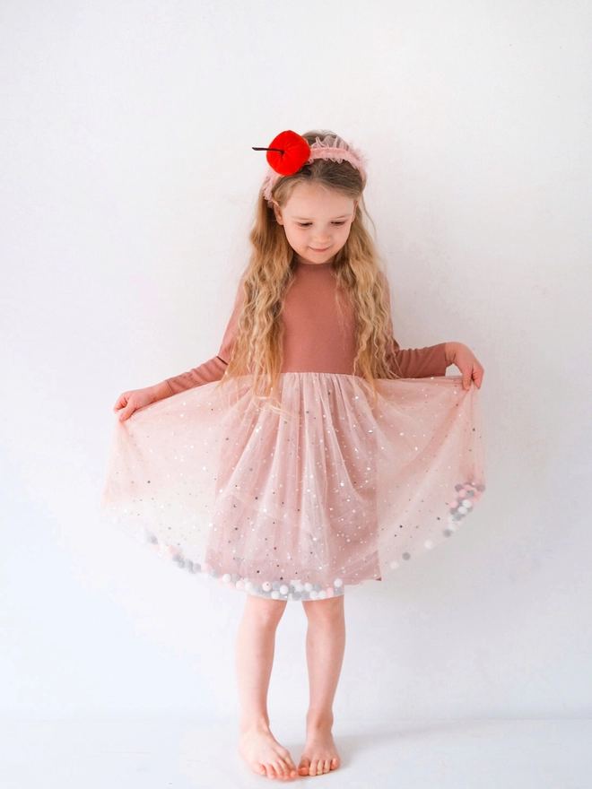 young girl posing wearing a pom pom tutu dress