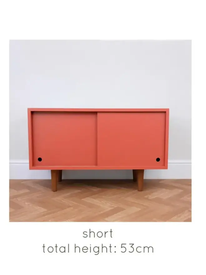 Mid-century cabinet with coral sliding doors and wooden tapered legs.