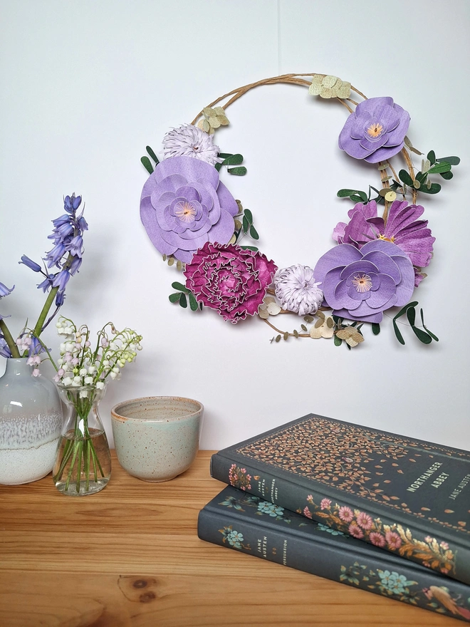 Handmade sculpture of a purple spring wreath of paper flowers, featuring peony, chrysanthemum, zinnia and camelia flowers