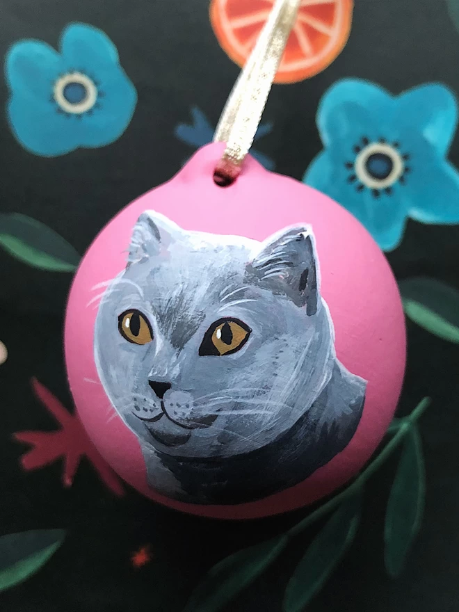 A Russian Blue Cat with amber eyes painted on to a pink Christmas ornament