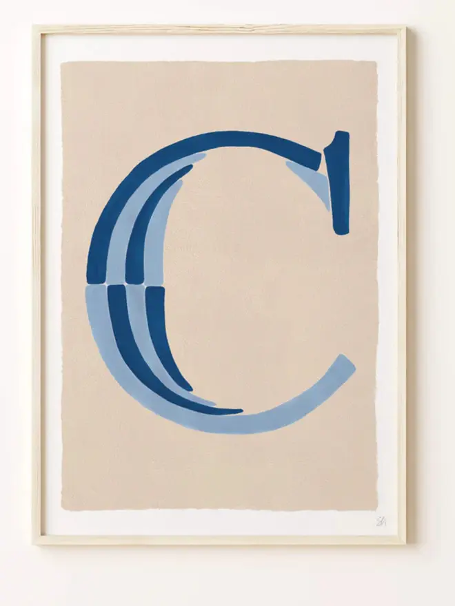 Framed wall art print featuring a large decorative letter “C” in humbug stripes
centered on a white background. 