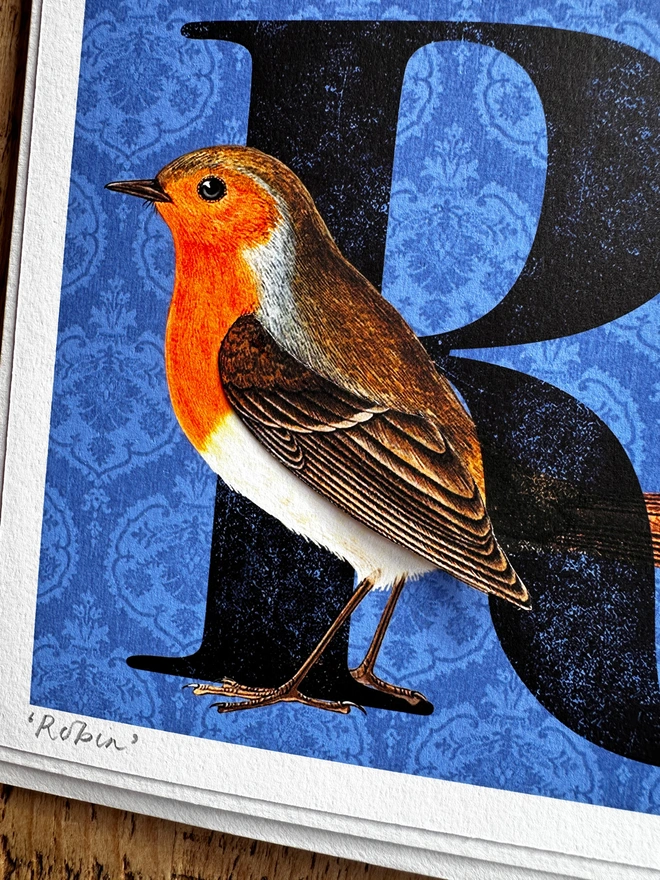 Close up photo of handmade card with a Robin on a blue background with a big letter R.