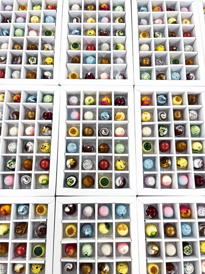 an assortment of different coloured chocolates in a white box