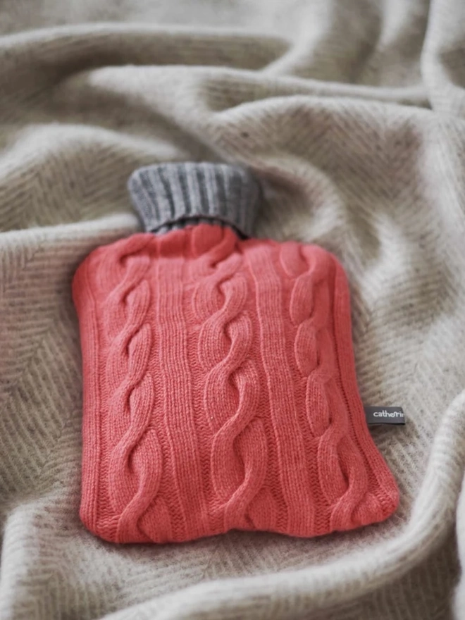 Cashmere Hot Water Bottle Cover, a colourful water bottle sitting on a blanket. 