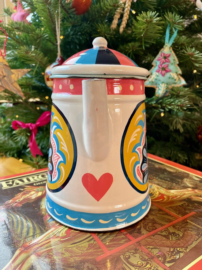 White enamel coffee pot hand painted with a fairground design in pink, yellow, and blue