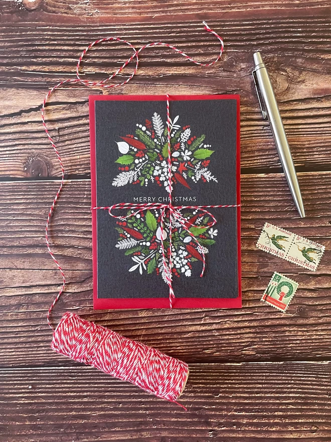 Bundle of 4 Christmas Cards Tied with Red and White Twine - Wooden Tabletop - Twine Spool, Christmas Postage Stamps, Silver Parker Pen