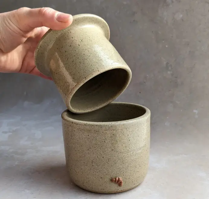 Croissant Butter Crock in biscuit glaze with a small croissant design on the front, set against a grey background.