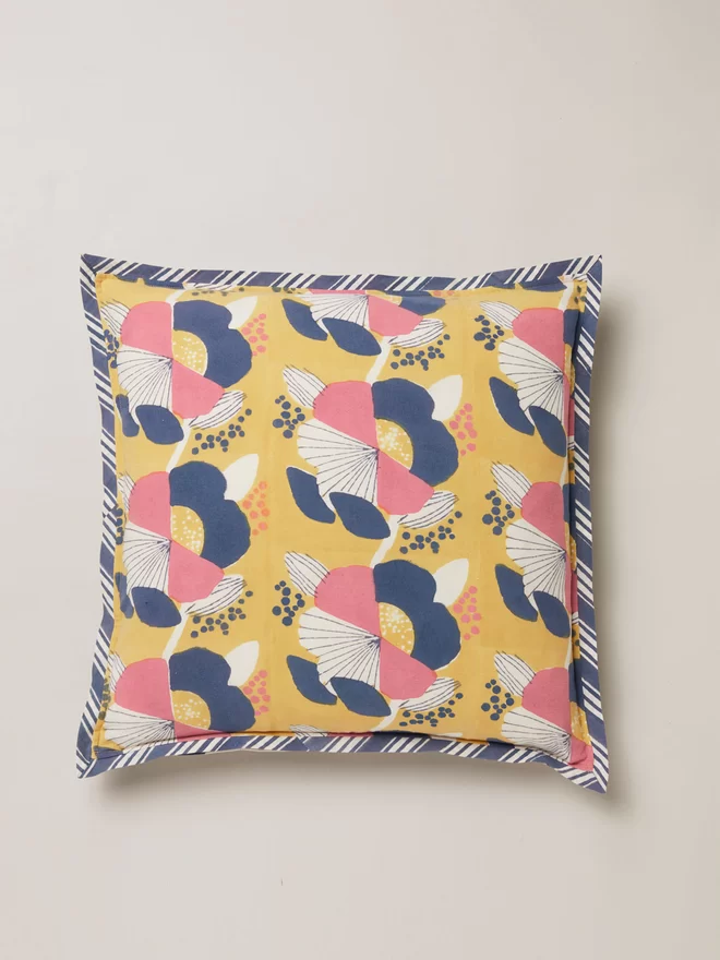 Block printed cushion featuring a large scale floral design in pink, cream and navy shades with a navy and cream strip border edging 