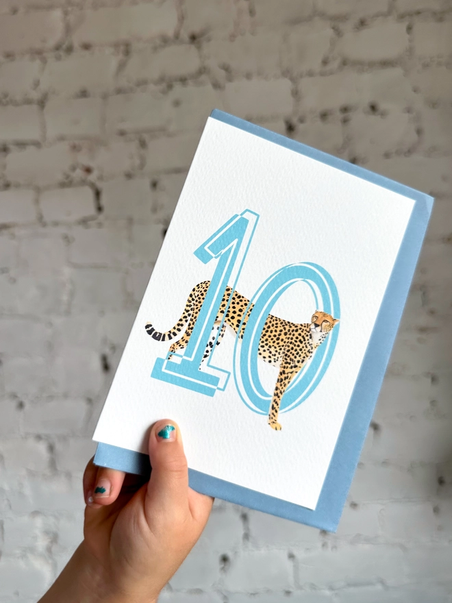 a white card with a big blue number 10 and an illustration of a cheetah with a pale blue envelope
