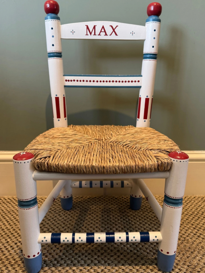 Toby Personalised Children’s Chair. A white chair with intricate blue and red designs.