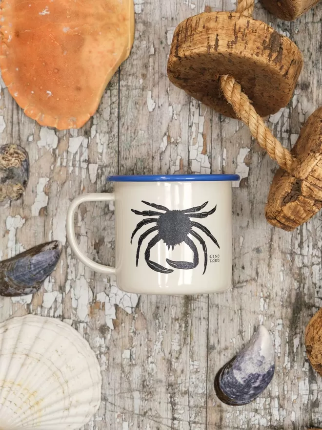 Picture of a Cream Enamel Mug with a Blue Rim with a Spider Crab design etched onto it, taken from an original Lino Print