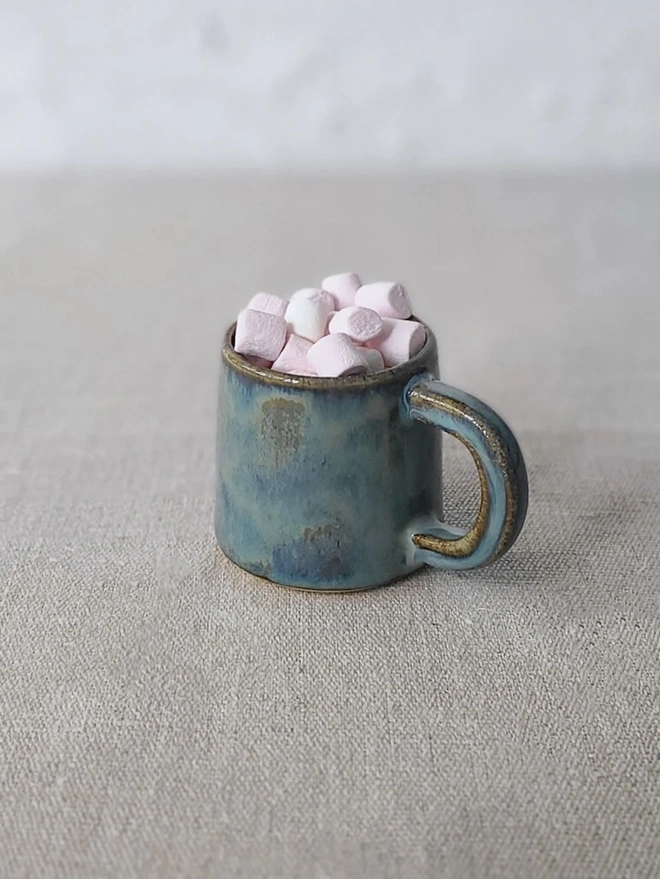 Classic Ceramic Espresso Mug, a colourful ceramic espresso mug sitting on a plain surface against a white backdrop. It is accompanied by a group of marshmallows. 