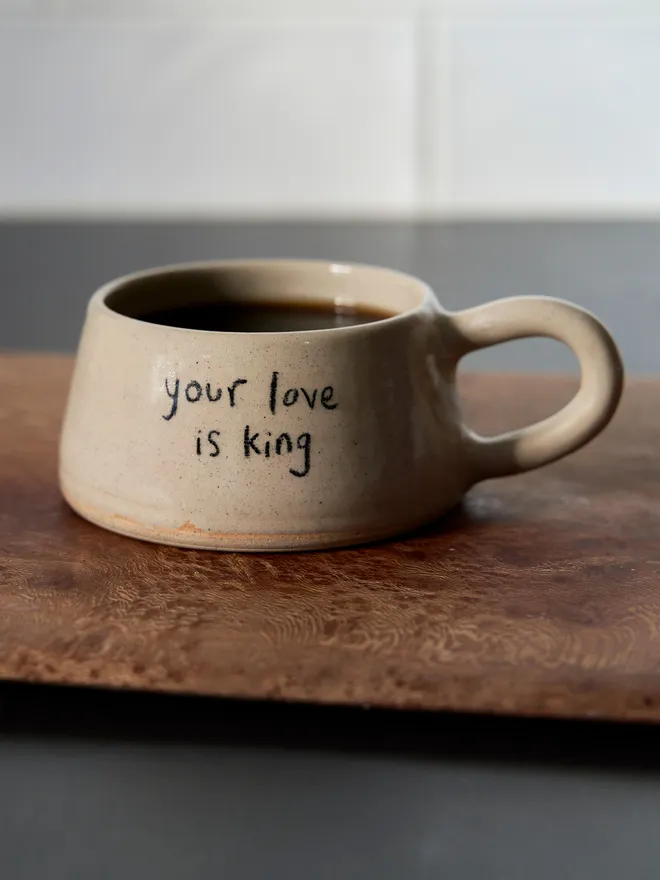 Cream ceramic mug with the words 'Your Love Is Kin' written on it 