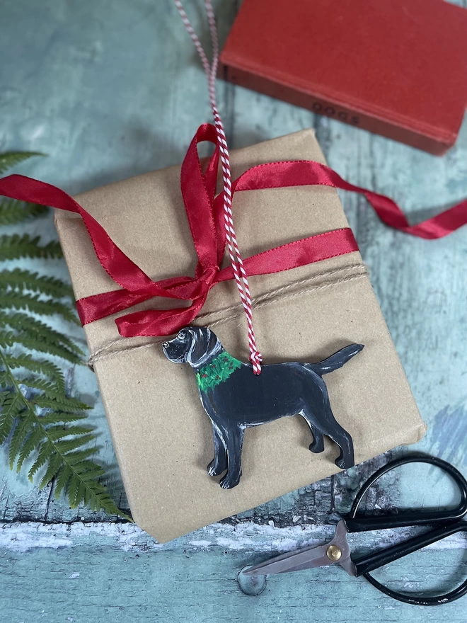 A Black Labrador Christmas decoration placed on a wrapped gift