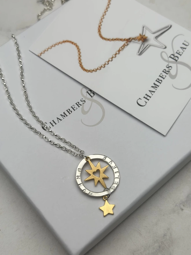 sterling silver chain with personalised silver halo charm. suspended within the halo is a gold starburst charm with cutout heart, with gold mini star suspended from the bottom of the halo